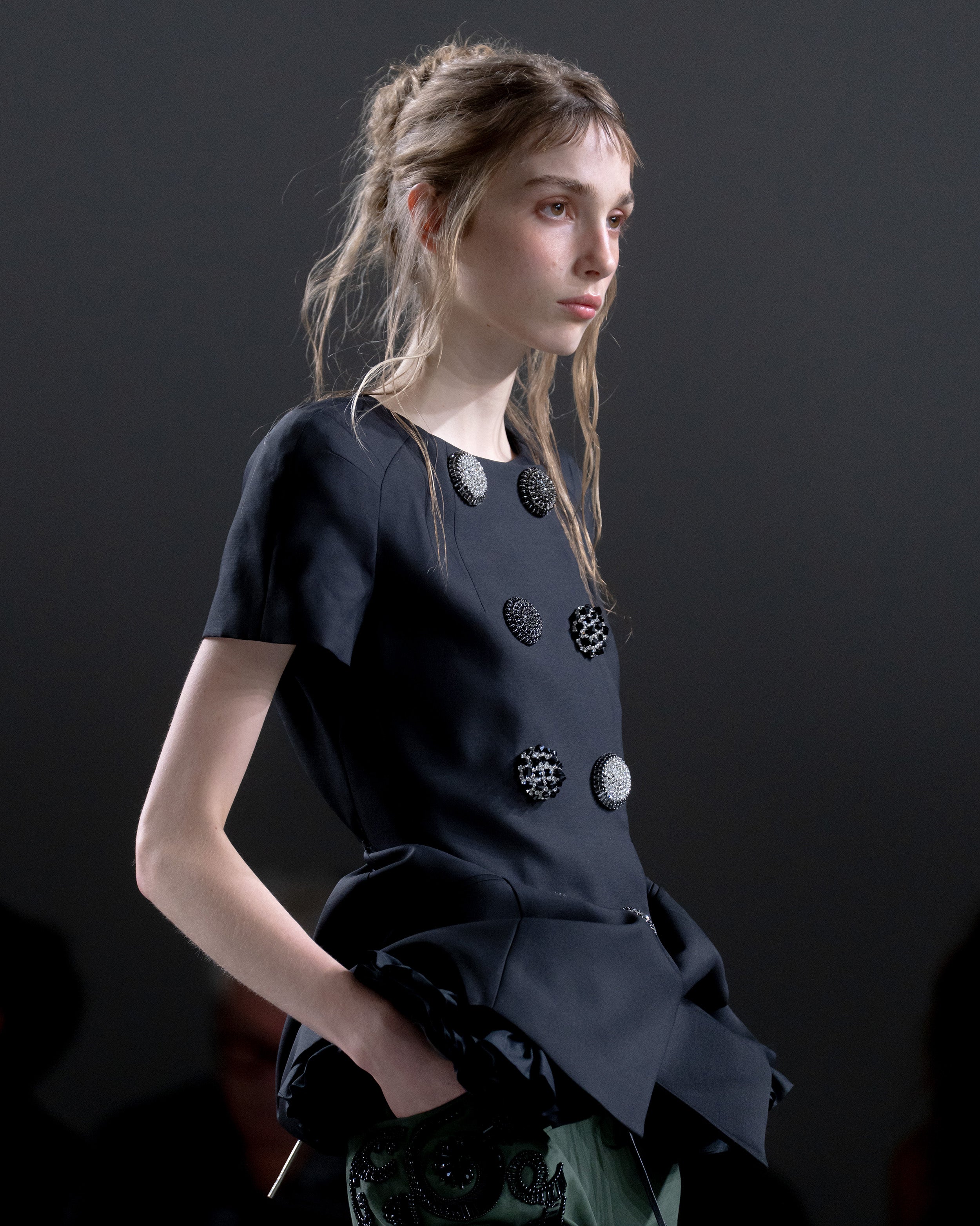 Model wearing a structured top with decorative circular embellishments 