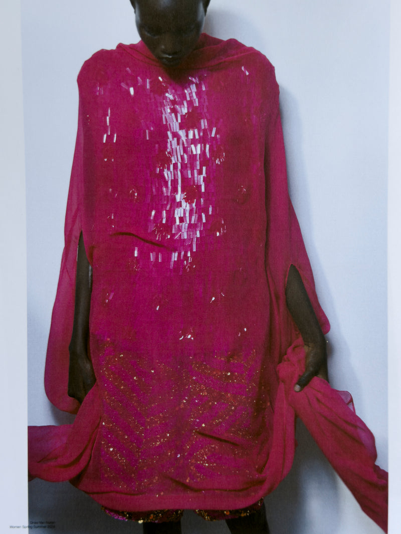 Person wearing a bright pink traditional outfit with sequin details on a white background