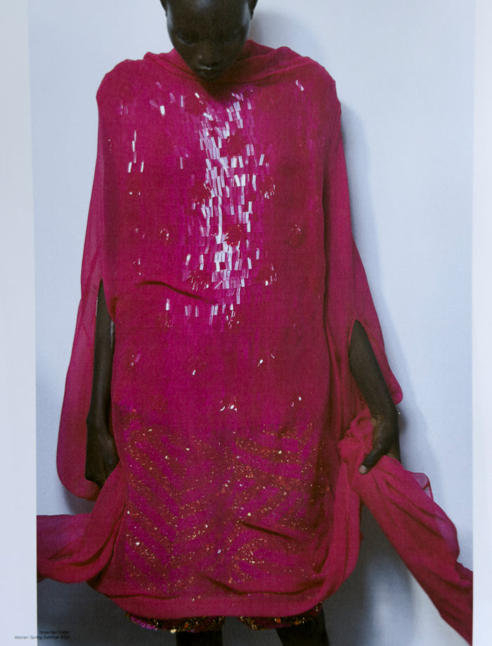 Person wearing a bright pink traditional outfit with sequin details on a white background