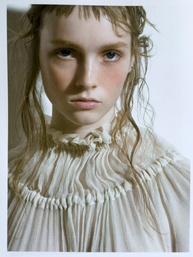 Person wearing a white, textured garment with a neutral background