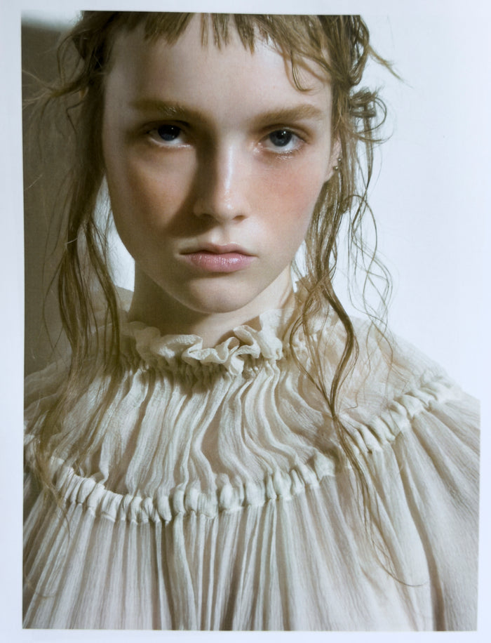 Person wearing a white, textured garment with a neutral background