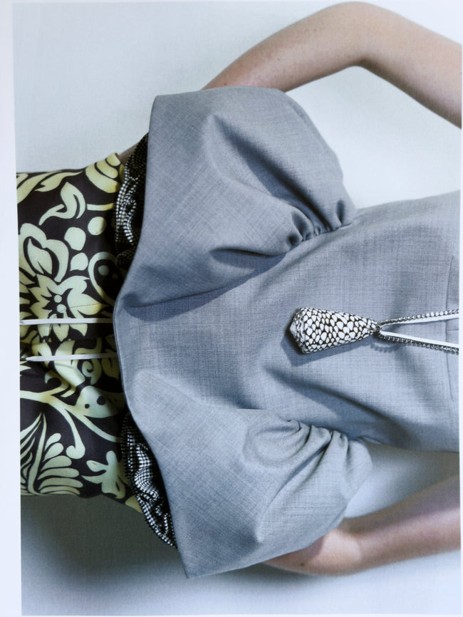 Close-up of a gray garment with a decorative brooch on a light background
