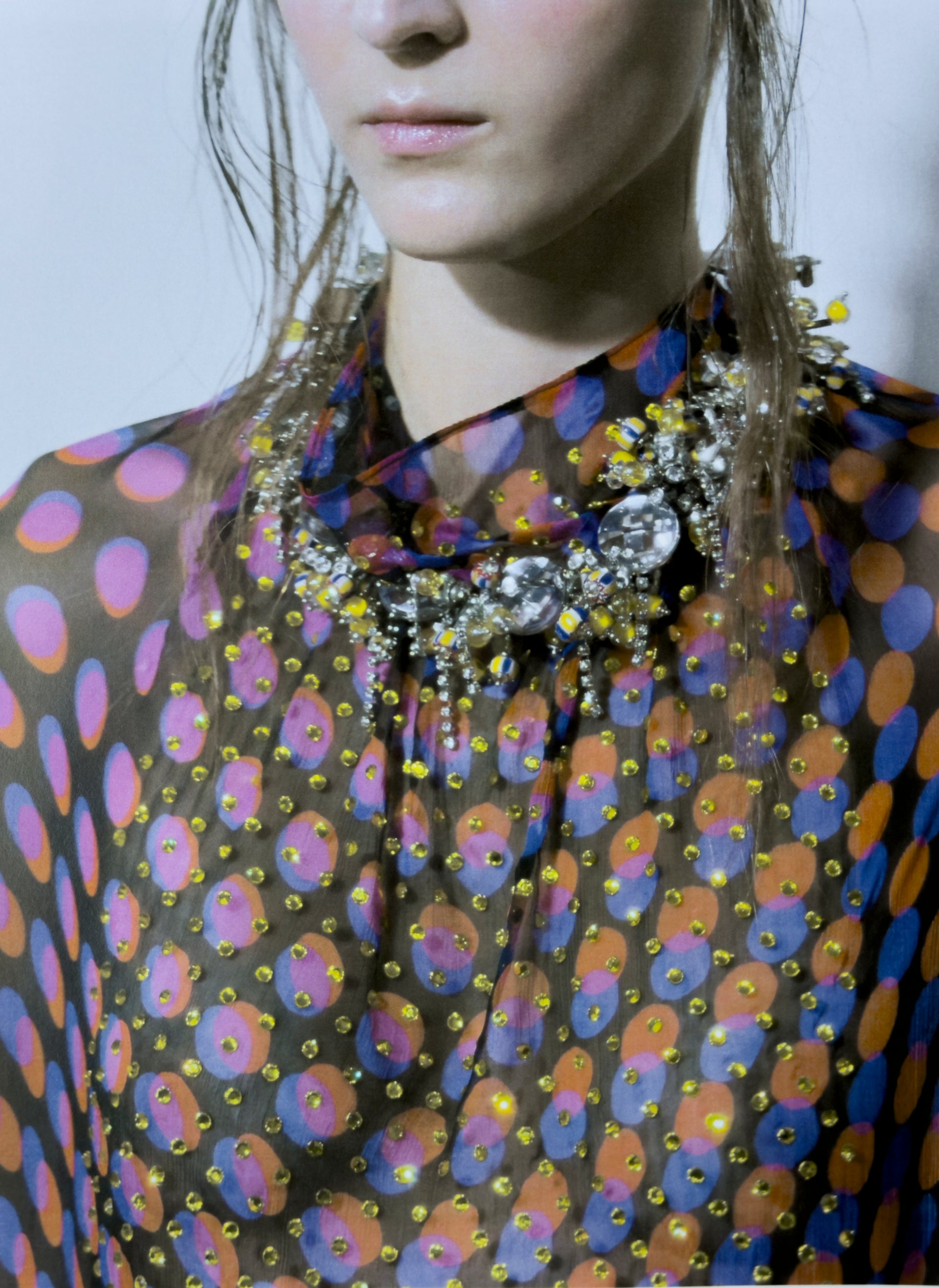Person wearing a colorful patterned garment with a prominent necklace.