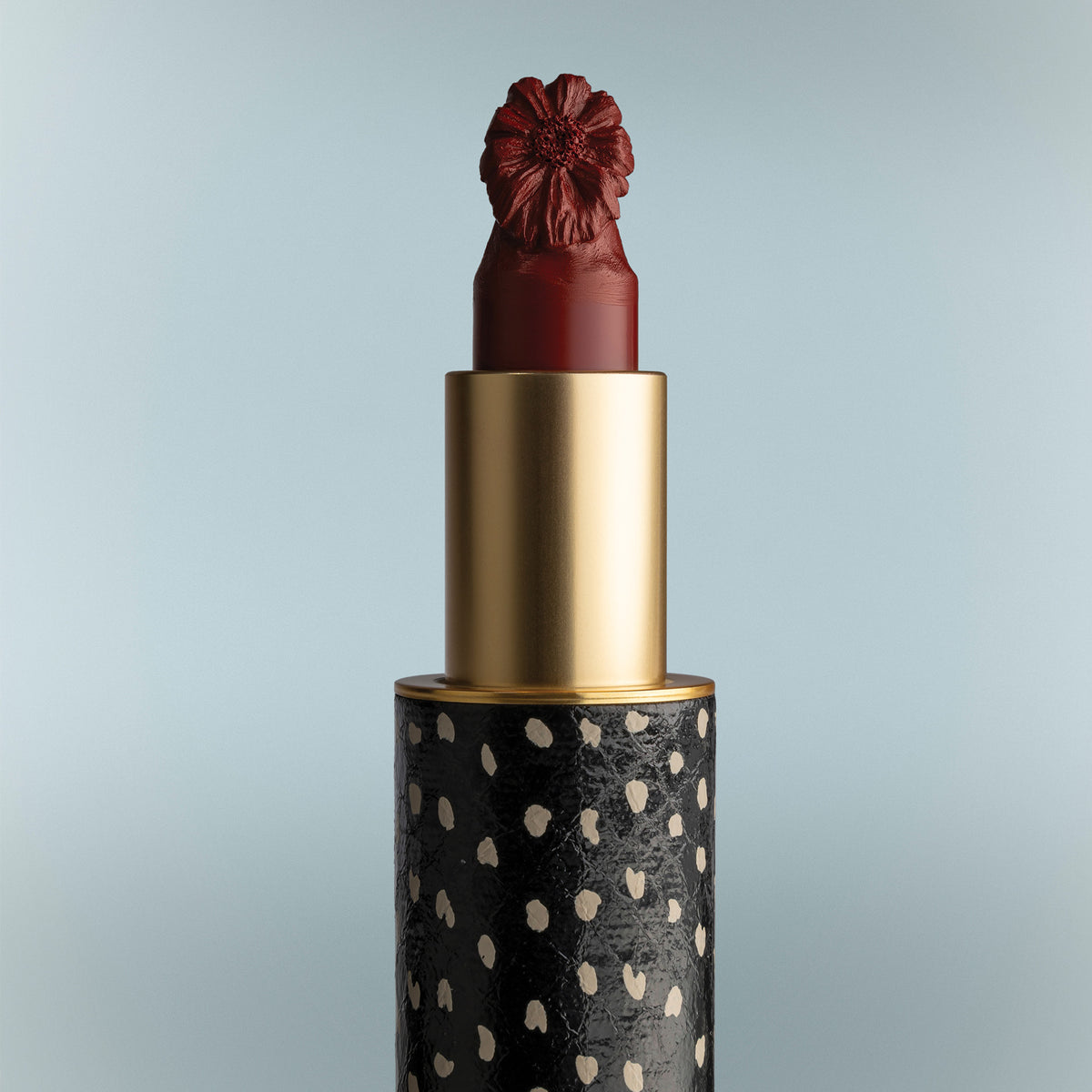 Lipstick with a decorative cap on a light blue background